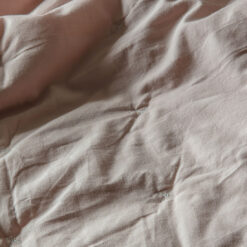 cotton blush pink bedspread with a white cross stitch design and flat pipe edging