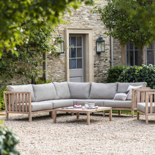 stylish outdoor wooden corner sofa lounge set with armchair and coffee table with a subtle whitewash and grey cushions